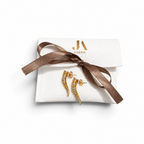 Jakris Zaria gold-plated brass earrings with sparkling zircon stones in a sculptural curved design on a gift pouch.