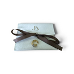 Jakris gold ear cuff with ridged design and four-leaf zircon stone detail, displayed on a branded white pouch.