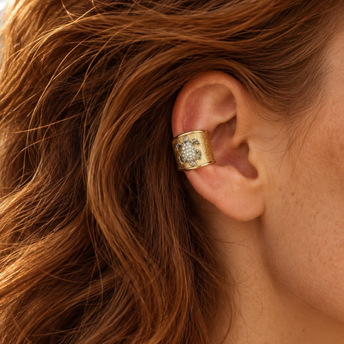 Jakris gold plated ear cuff featuring a textured surface and a sparkling zircon stone turtle design on a woman's ear