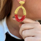 Jakris Rossa statement earrings featuring 24k gold-plated textured metal and vibrant red coral beads on a model.