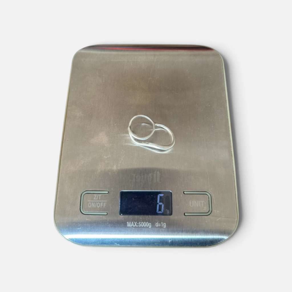 Jakris Reilly gold-plated two-finger ring resting on a digital kitchen scale showing 6 grams weight