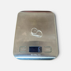 Jakris Reilly gold-plated two-finger ring resting on a digital kitchen scale showing 6 grams weight