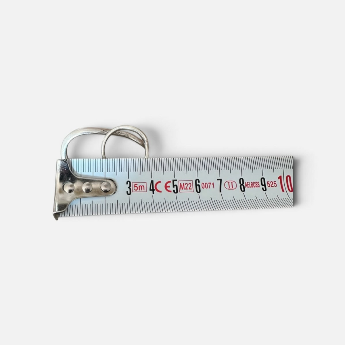 Jakris Reilly gold-plated two-finger ring resting on a metal measuring tape against a white background