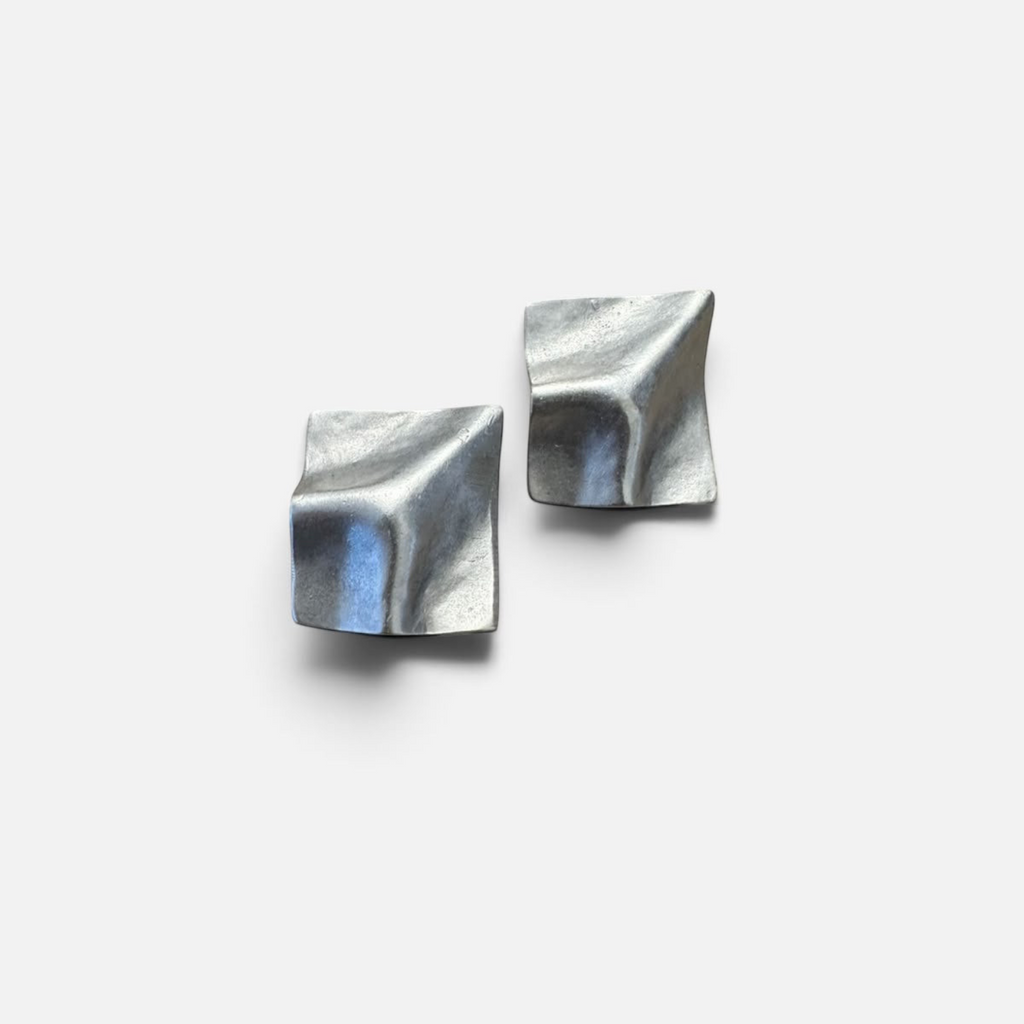 Jakris Noila sculptural silver-toned earrings with a geometric, curved square design and organic textured surface.