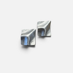Jakris Noila sculptural silver-toned earrings with a geometric, curved square design and organic textured surface.