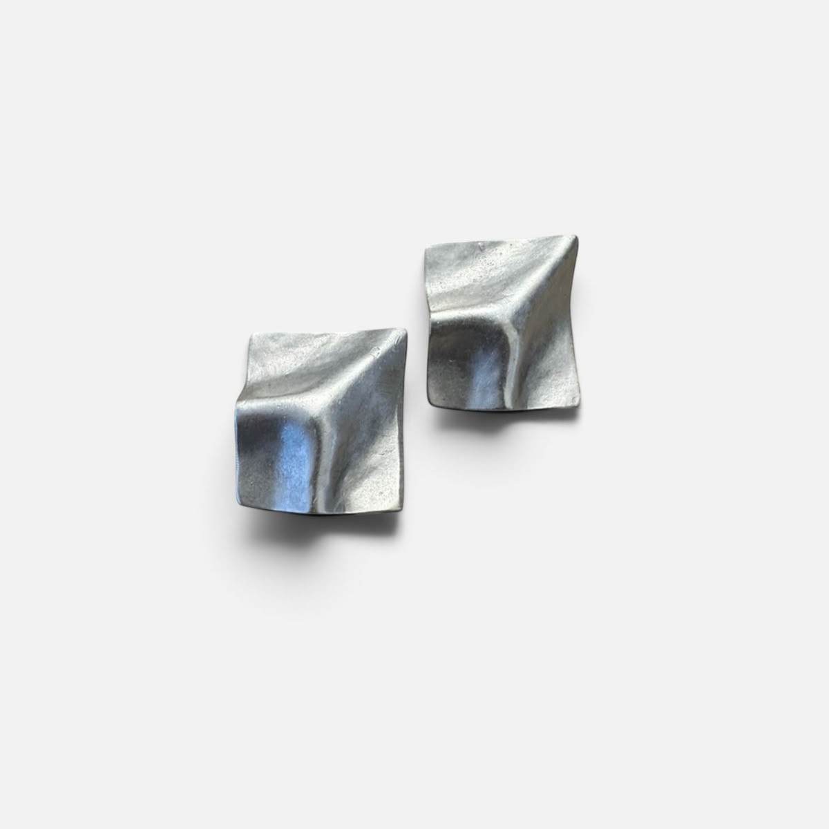 Jakris Noila sculptural silver-toned earrings with a geometric, curved square design and organic textured surface.