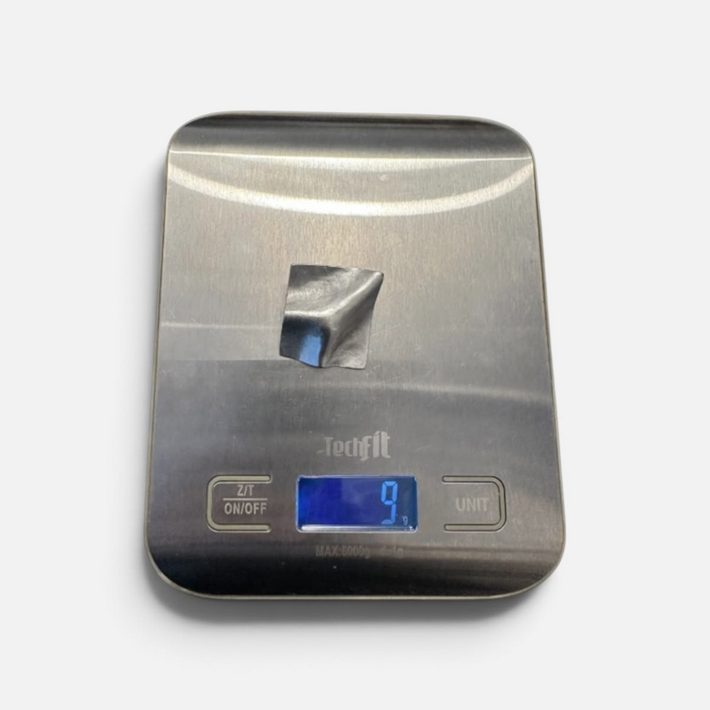 Jakris Noila sculptural silver-toned earring on a digital scale showing a weight of 9 grams.