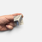 Jakris Noila sculptural silver-tone square earring with a curved, organic surface held in a hand.