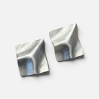 Jakris Noila sculptural silver-toned earrings with a geometric, curved square design and organic textured finish.