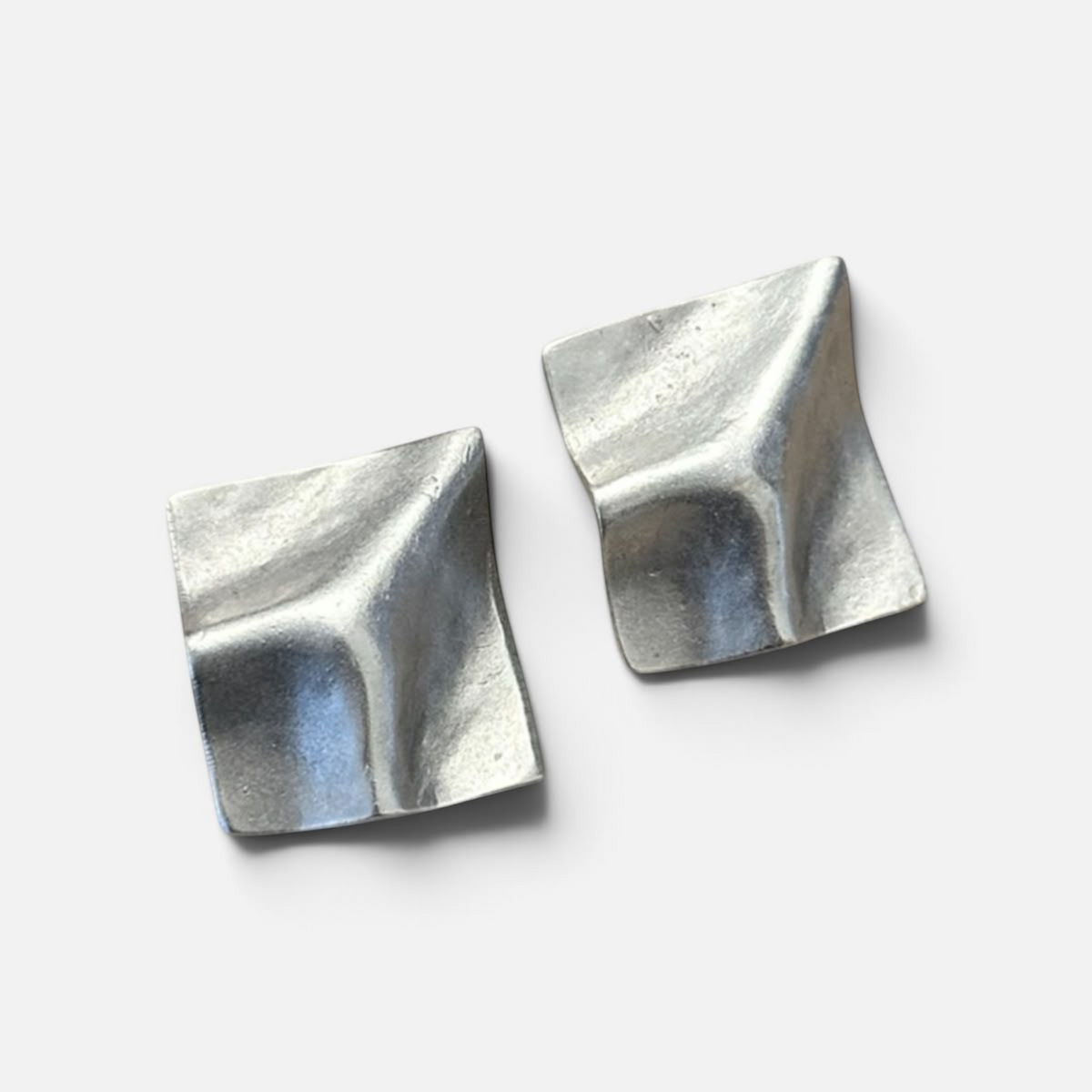 Jakris Noila sculptural silver-toned earrings with a geometric, curved square design and organic textured finish.