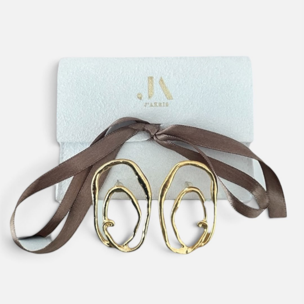 Jakris gold plated abstract oval earrings with textured surface and asymmetric design in a branded gift box.
