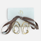 Jakris gold plated abstract oval earrings with textured surface and asymmetric design in a branded gift box.
