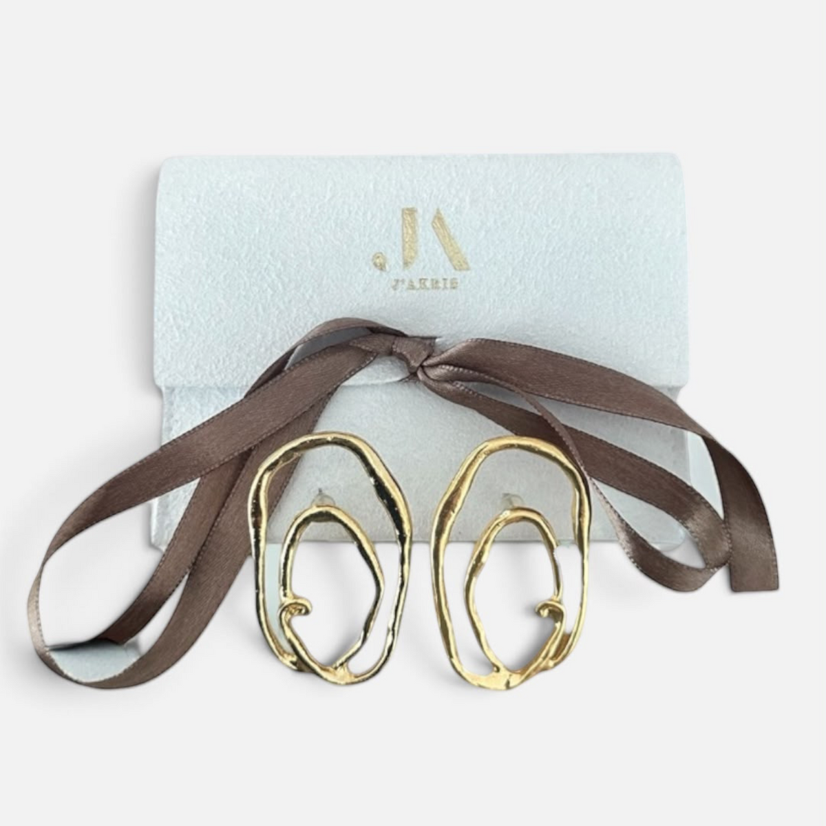 Jakris gold plated abstract oval earrings with textured surface and asymmetric design in a branded gift box.