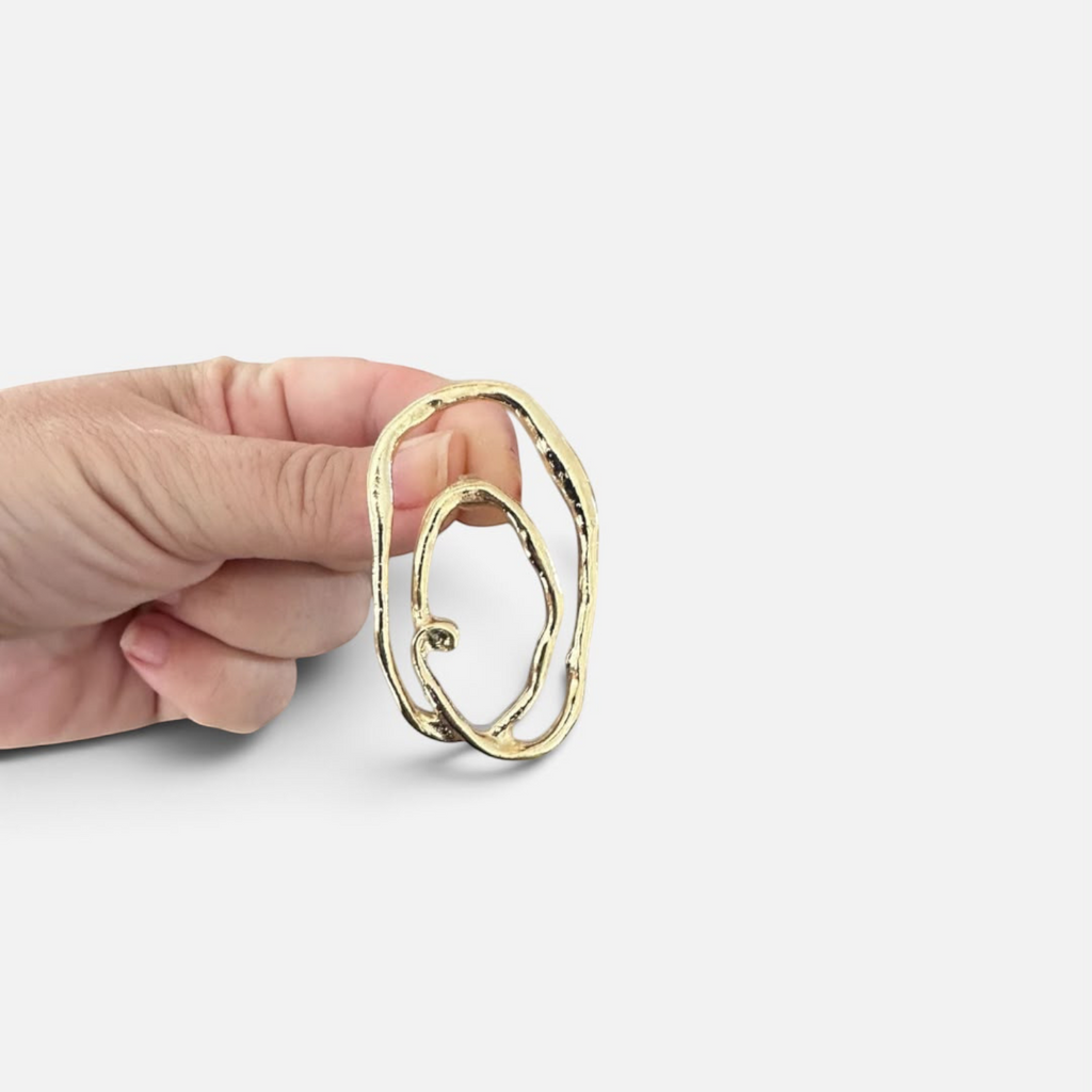 Jakris Alara gold plated abstract oval earring with textured surface held in hand