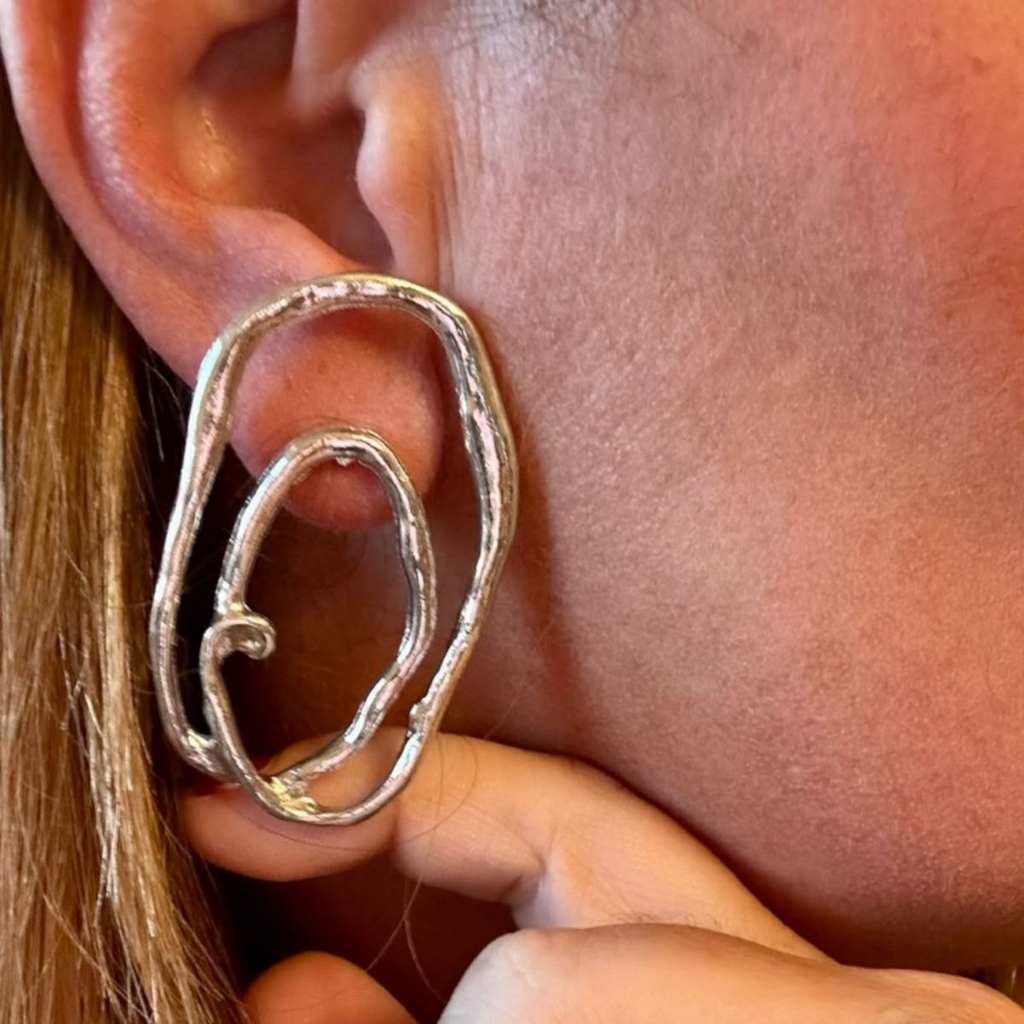 Jakris Alara silver-plated abstract oval earrings with a textured organic finish worn on a model ear.
