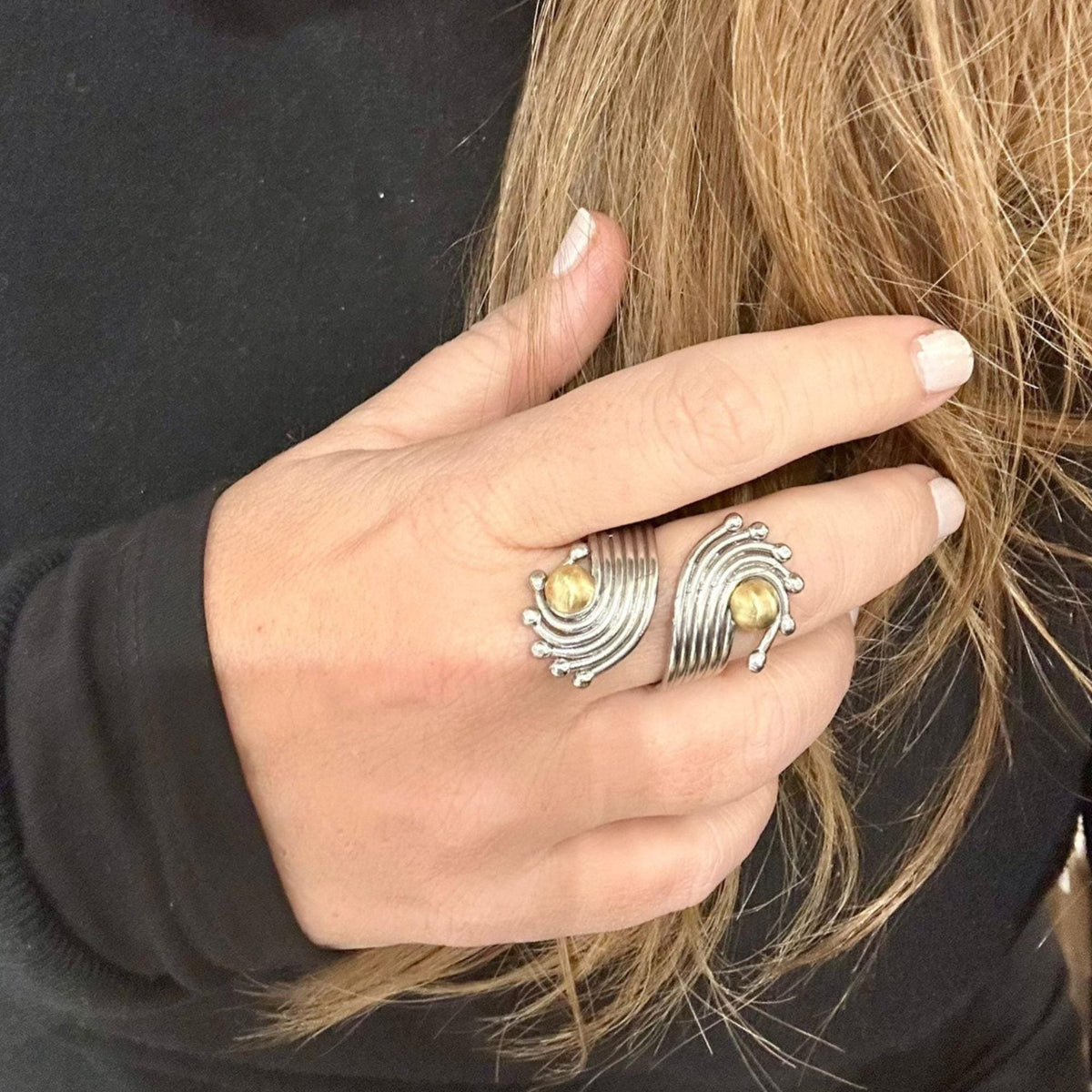 Jakris handmade adjustable ring in brass and white gold rhodium plating with a unique curved design on a hand