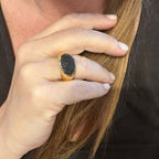 Jakris adjustable gold ring featuring a pavé-set black zircon oval stone worn on a woman's finger