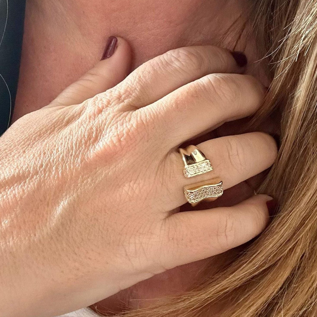 Jakris adjustable gold-plated ring featuring a modern open design with sparkling crystal accents on a woman's hand.