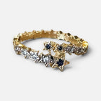 Jakris adjustable gold ring featuring a star-shaped crossover design with sparkling clear and dark blue stones.