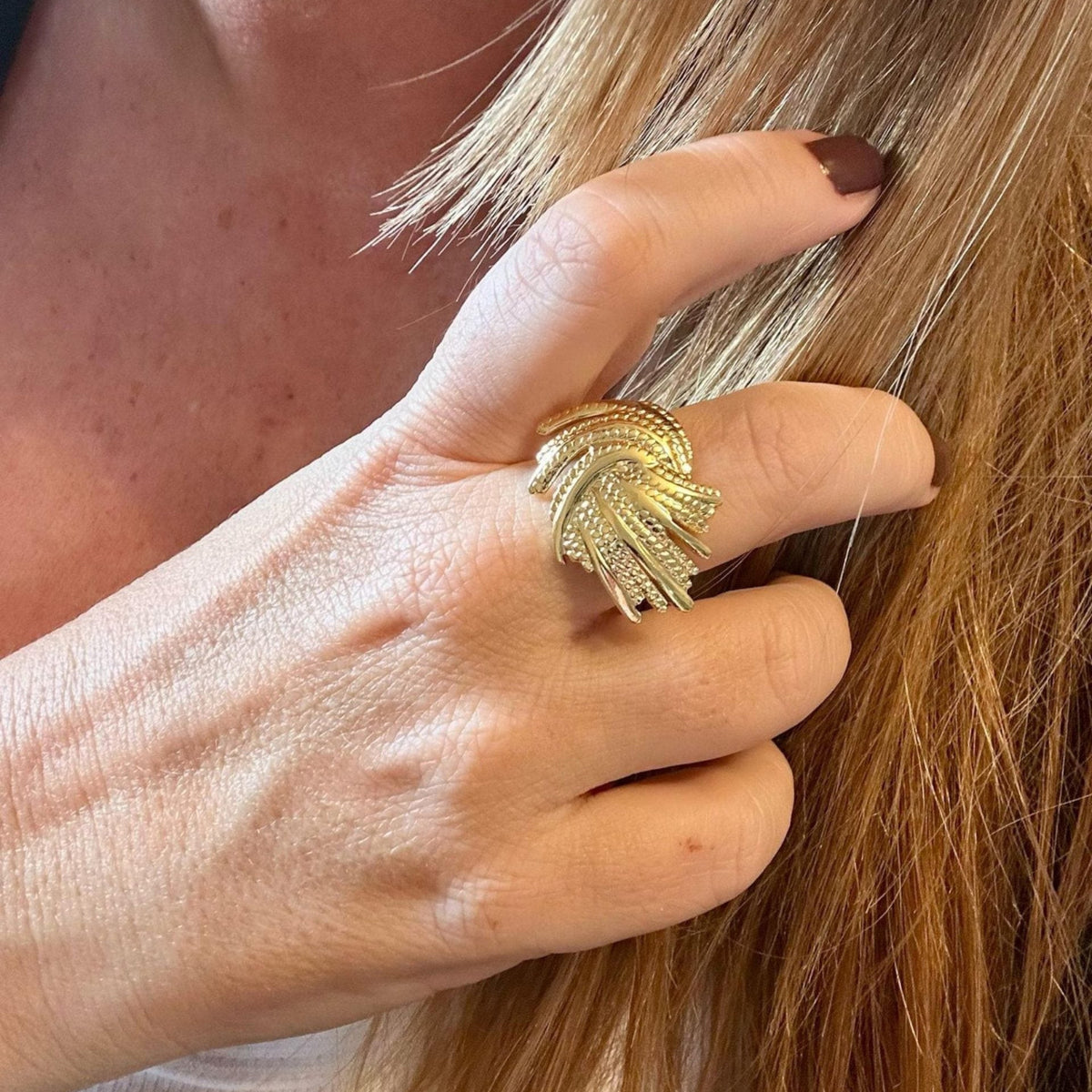 Jakris adjustable gold ring with a textured, nature-inspired leaf design worn on a woman's finger