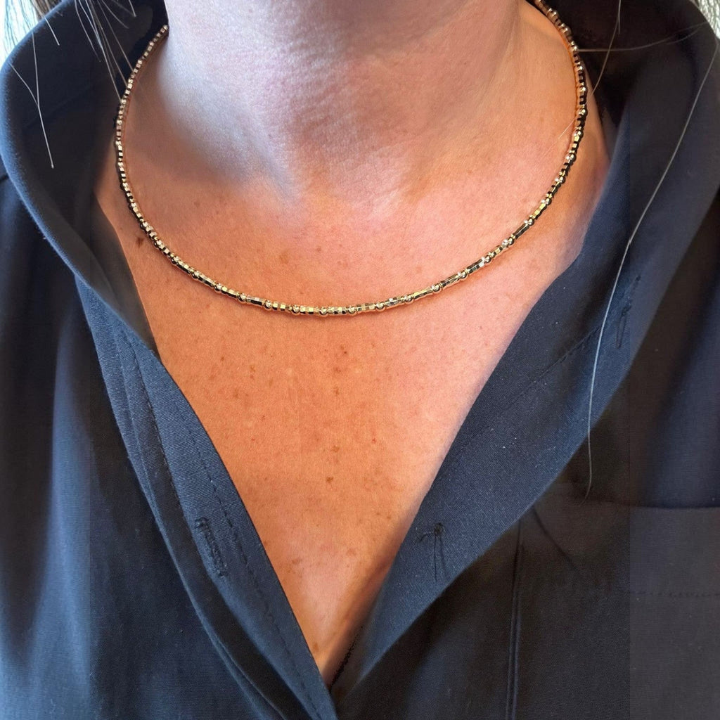 Jakris adjustable thin gold choker necklace with delicate metallic beads worn around the neck
