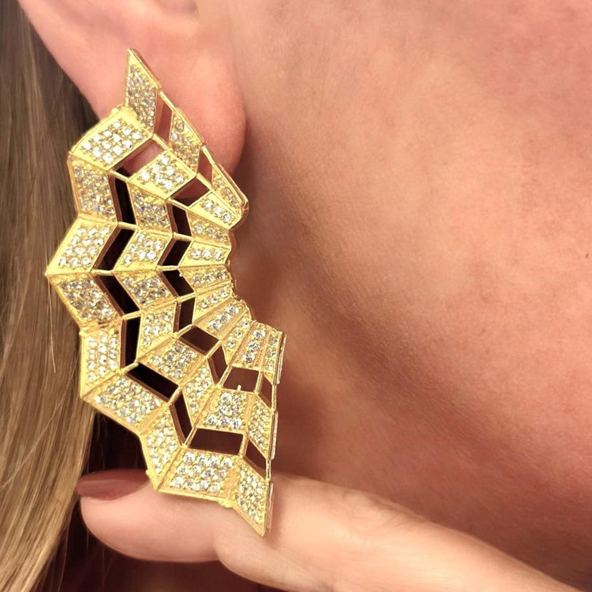 Jakris Art Deco fan-shaped gold earrings adorned with sparkling zircon stones worn on an ear