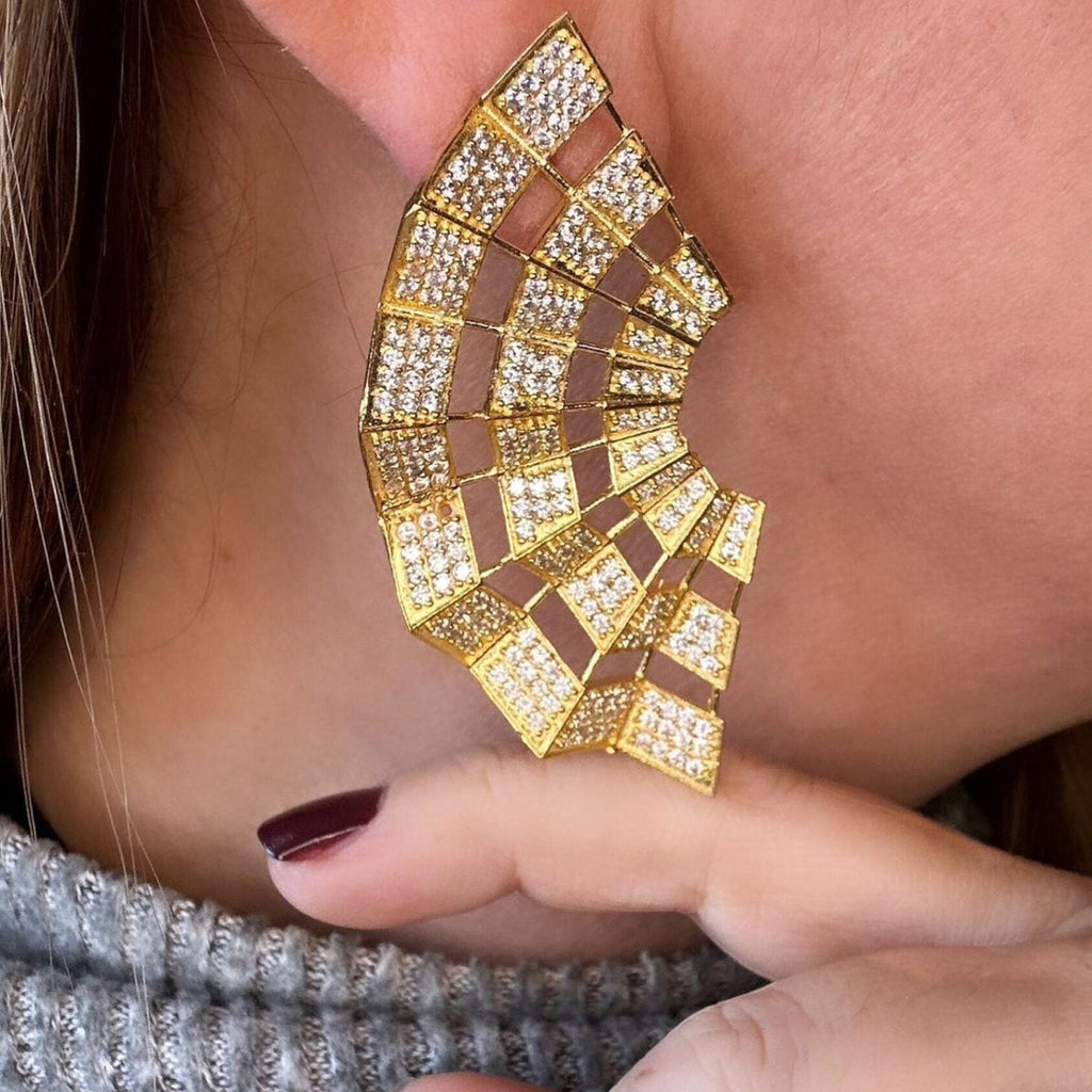 Jakris Art Deco fan-shaped gold earrings adorned with sparkling zircon stones worn on an earlobe