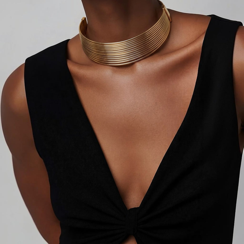 Jakris Aura altın rengi çok sıralı metal choker kolye, siyah elbise üzerinde modern ve şık bir görünüm sunuyor.