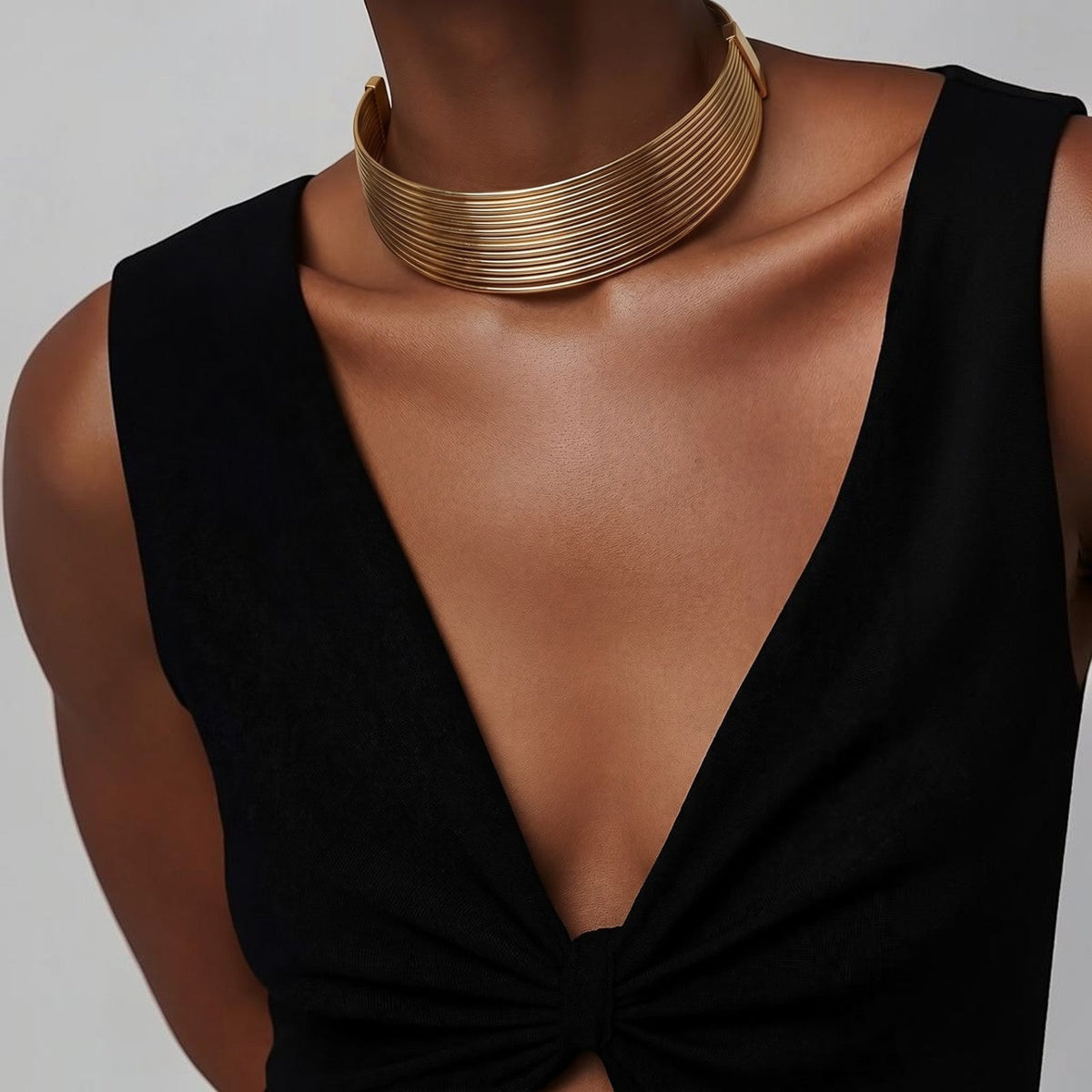 Jakris Aura altın rengi çok sıralı metal choker kolye, siyah elbise üzerinde modern ve şık bir görünüm sunuyor.