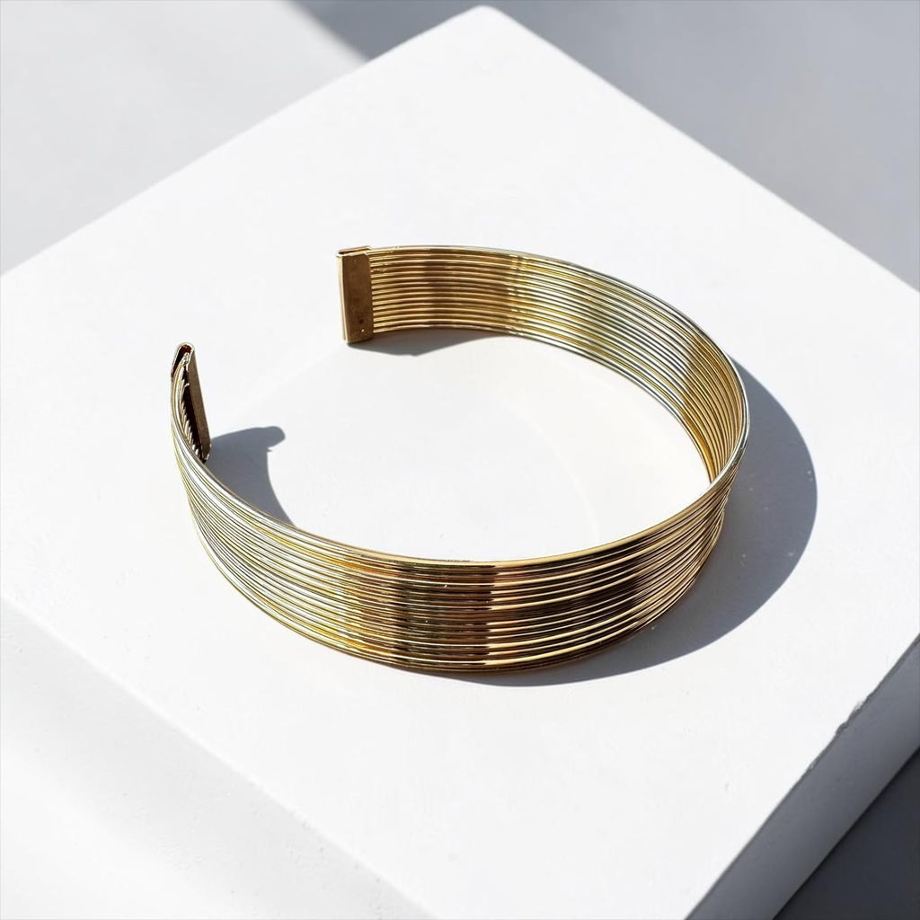 Jakris marka, beyaz zemin üzerinde sergilenen, çok sıralı metal tasarıma sahip modern altın rengi choker kolye.