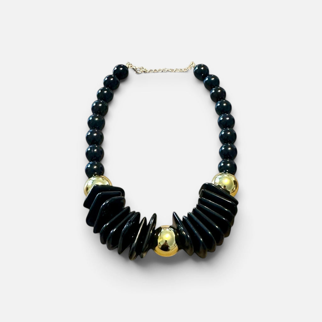 Jakris black chunky beaded statement necklace with gold-tone accents and geometric design on a marble surface