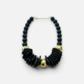Jakris black chunky beaded statement necklace with gold-tone accents and geometric design on a marble surface