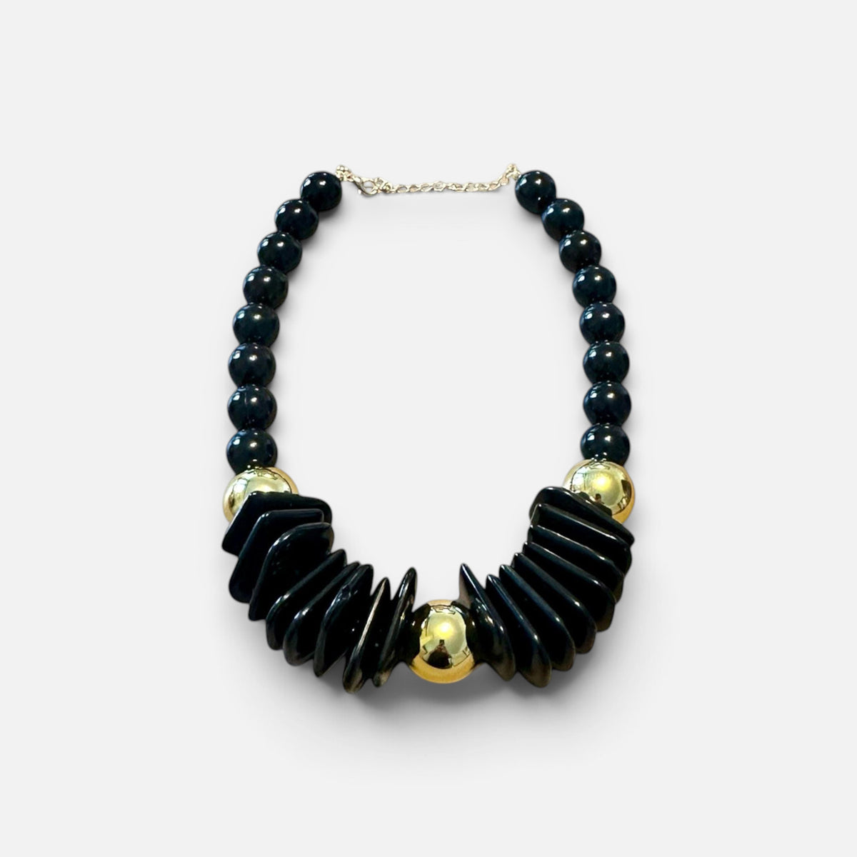 Jakris black chunky beaded statement necklace with gold-tone accents and geometric design on a marble surface