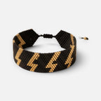 Jakris woven beaded bracelet in black and gold with a lightning bolt pattern and adjustable drawstring closure.
