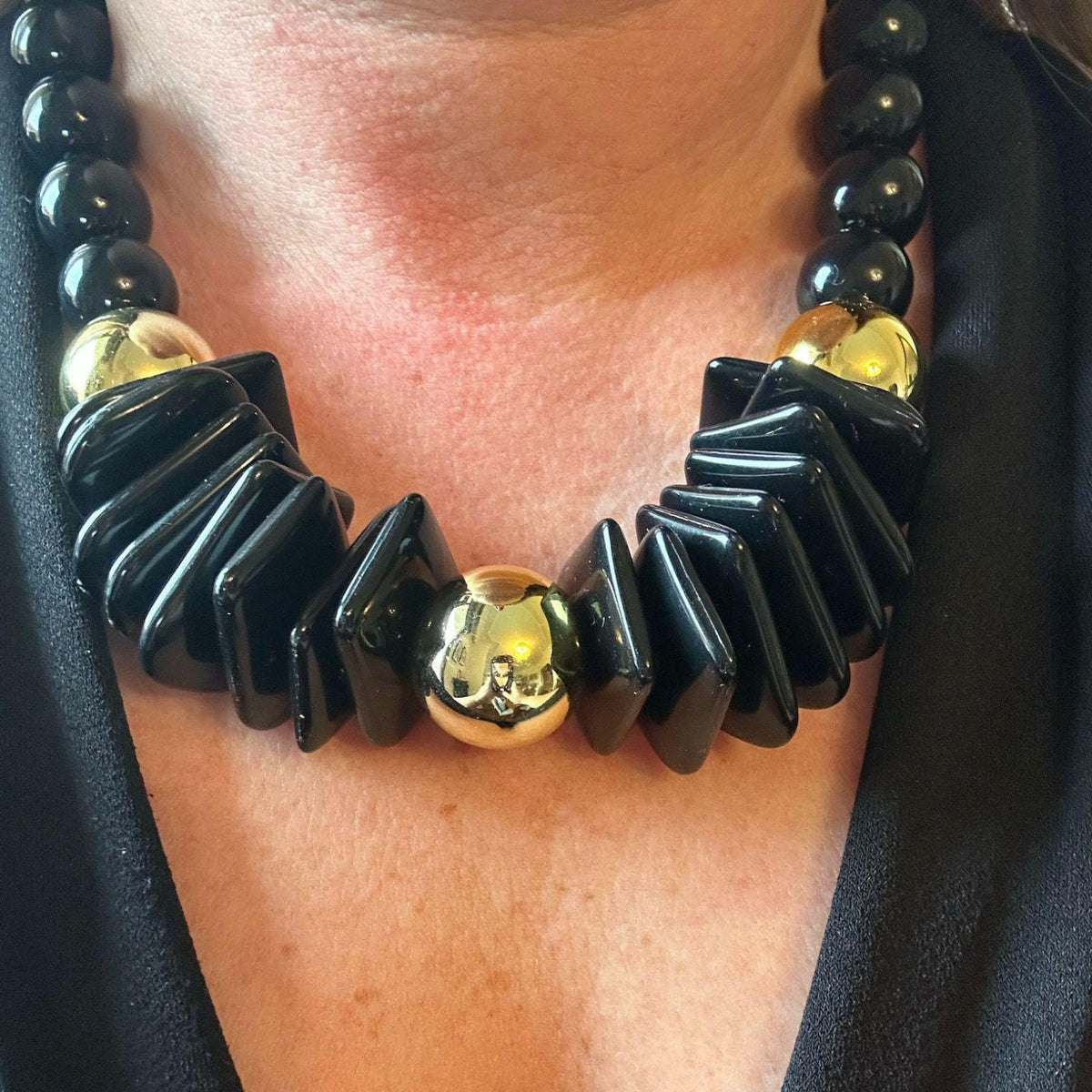 Jakris black and gold geometric statement necklace featuring chunky beads and square accents worn on a person