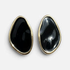 Jakris black oval earrings with a smooth glossy finish and gold-toned metal trim on a white background.