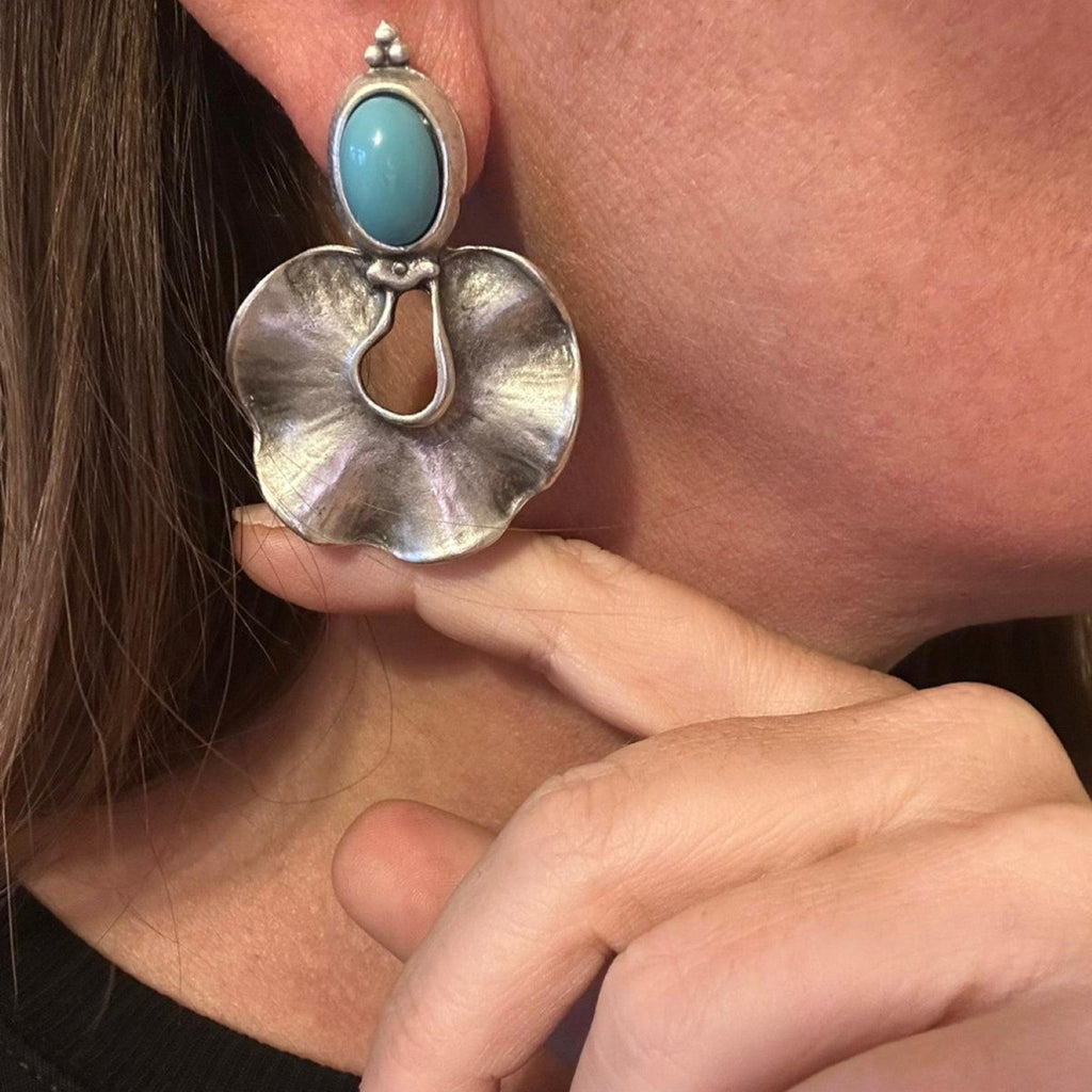 Jakris statement earrings featuring a blue stone and organic silver-plated brass design worn on a person's ear.
