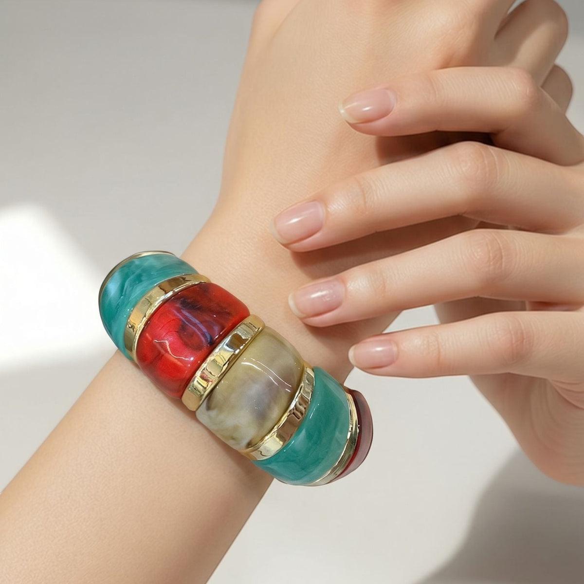 Jakris elastic bracelet featuring vibrant color-blocked resin segments and gold-toned accents on a woman's wrist.