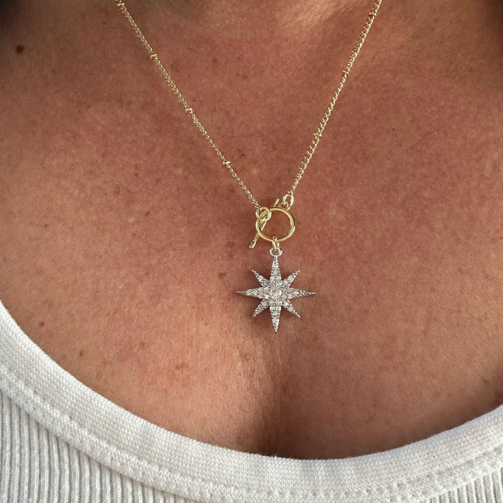 Jakris gold-tone crystal North Star pendant necklace with an adjustable toggle chain worn on a person