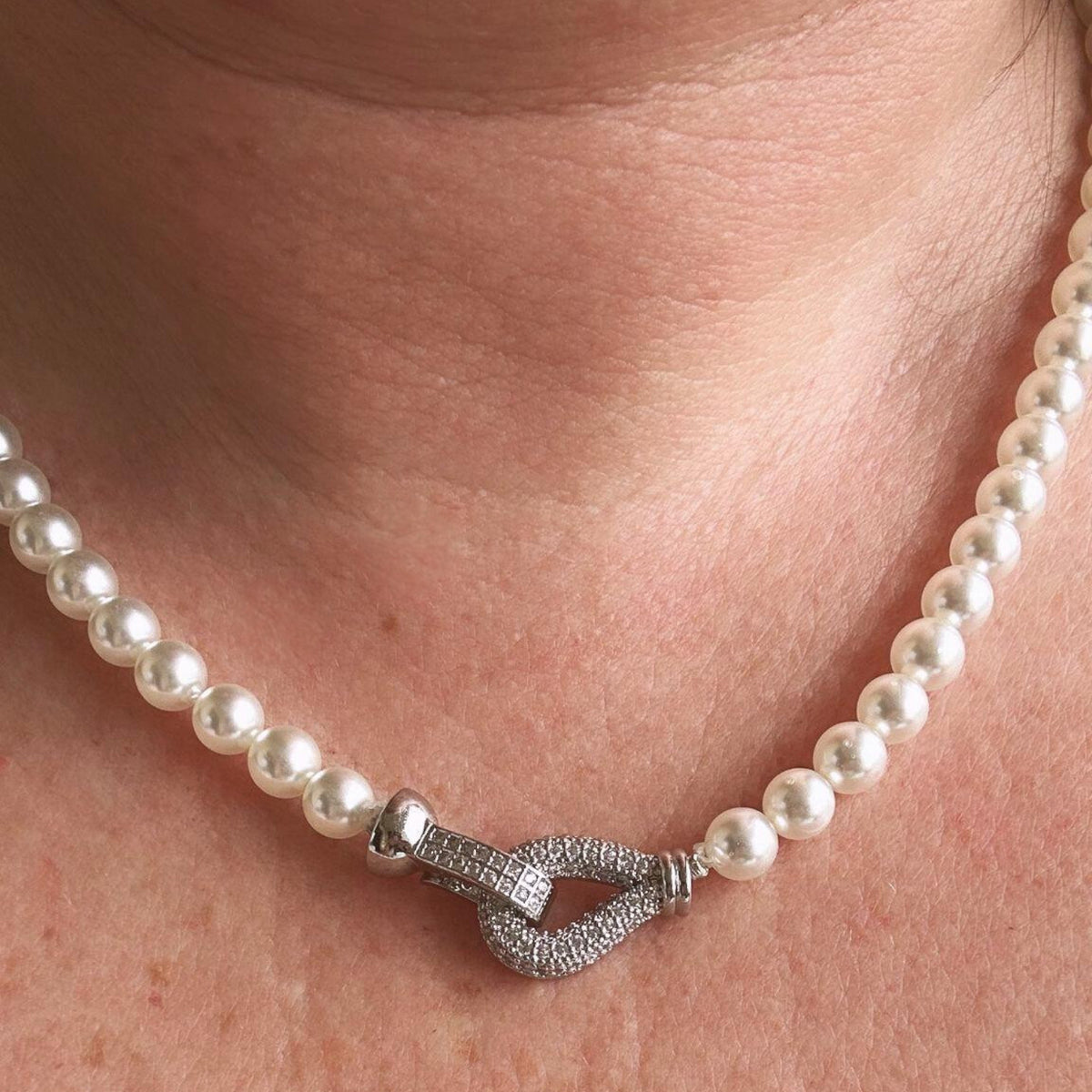 Jakris freshwater pearl choker necklace featuring a sparkling zircon-encrusted clasp worn around the neck