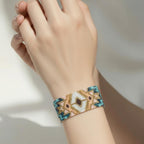 Jakris woven bead bracelet featuring a geometric pattern in metallic gold, turquoise, and soft pink on a wrist.