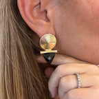 Jakris modern geometric gold-plated earrings featuring a black triangular stone worn on a woman's ear