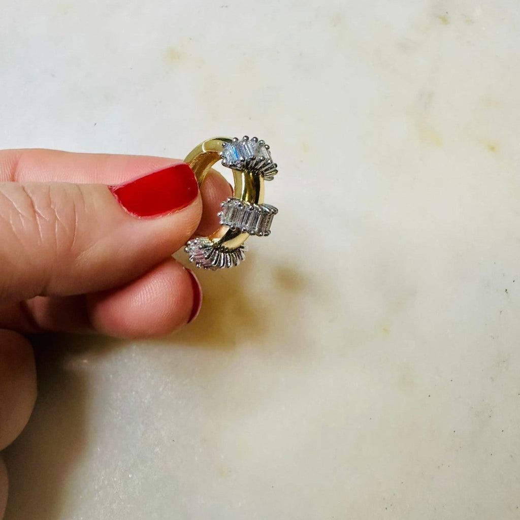 Jakris gold hoop earring featuring small baguette cut stones held by a hand with red nail polish