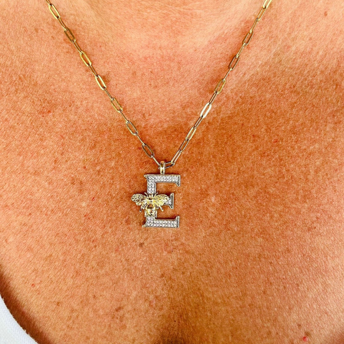 Jakris gold letter E pendant necklace featuring a sparkling zircon-encrusted design with a small bee detail
