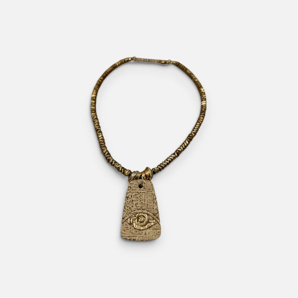 Jakris gold-plated brass beaded necklace featuring a textured pendant with an embossed evil eye symbol