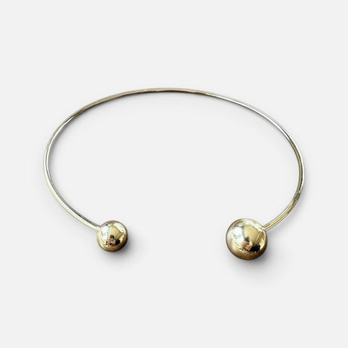 Jakris gold-plated brass open collar necklace featuring two asymmetrical polished spheres in a minimalist design.