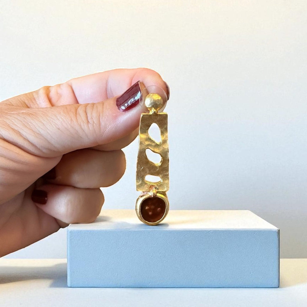 Jakris designer earring featuring a gold-tone abstract cutout metal frame and a round brown stone drop