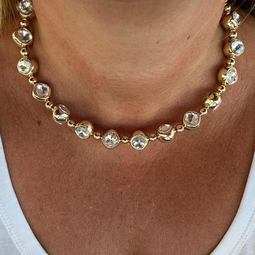 Jakris gold-tone choker necklace featuring large round clear crystals and metallic beads worn around the neck