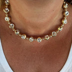 Jakris gold-tone choker necklace featuring large round clear crystals and metallic beads worn around the neck