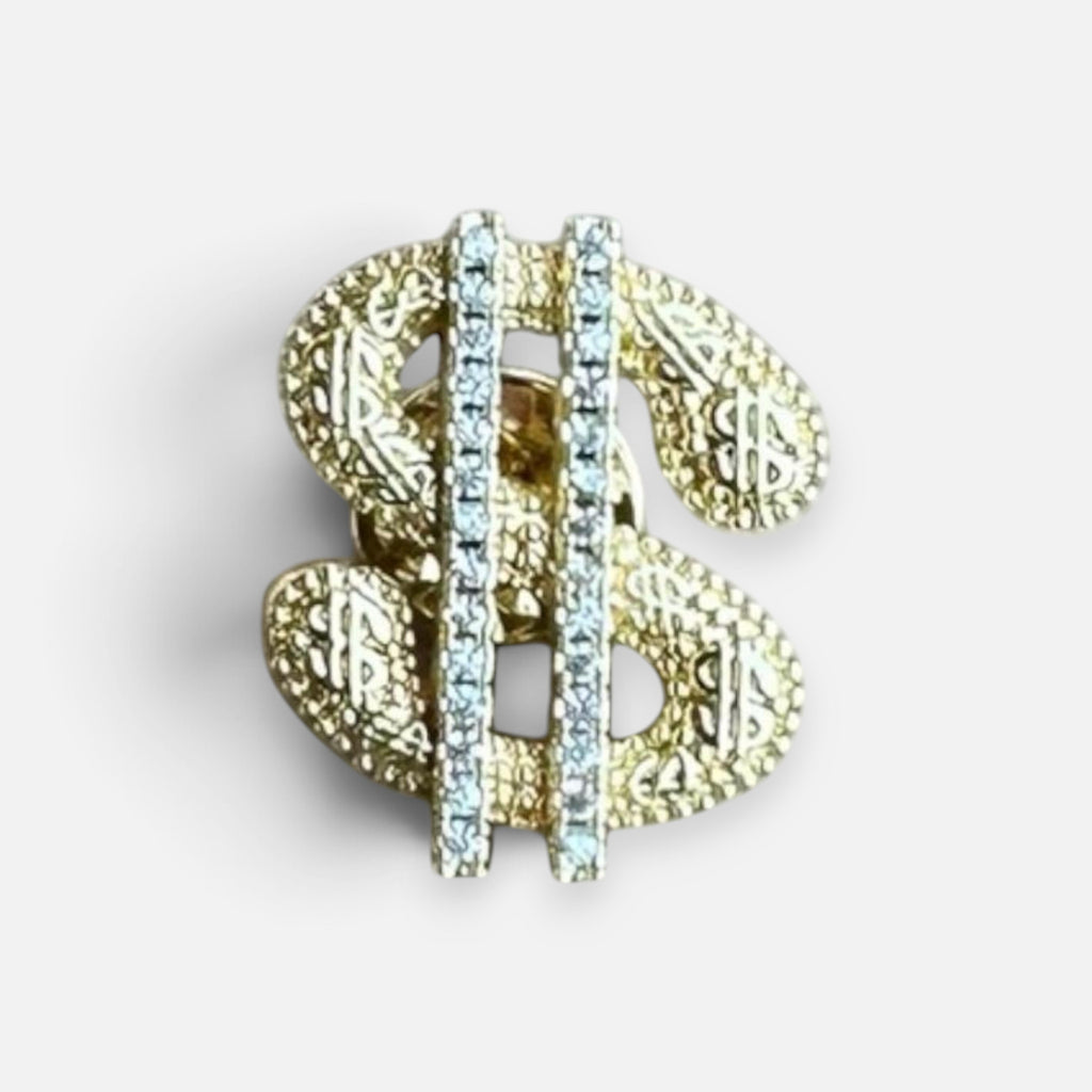 Jakris gold-tone dollar sign brooch featuring a textured surface and a vertical row of sparkling clear crystals.